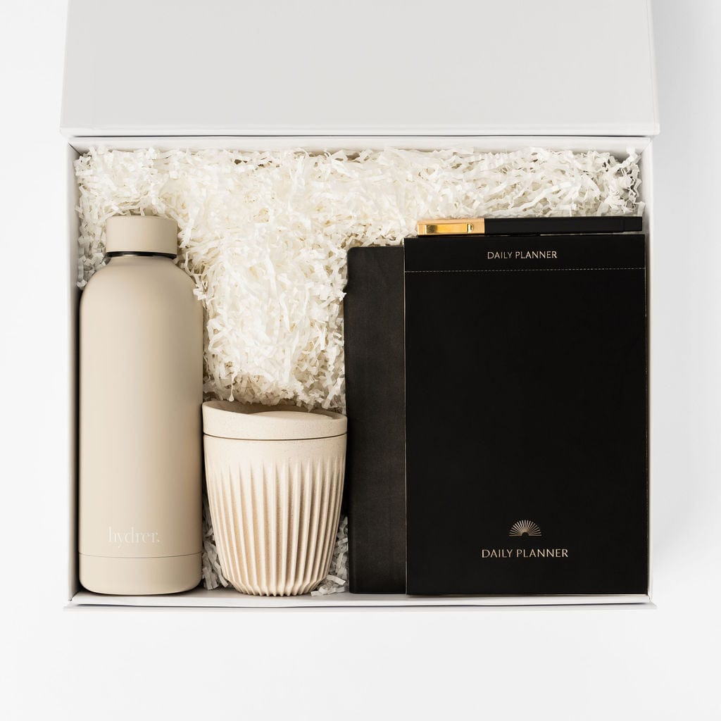 Luxury soft touch insulated water bottle in beige, huskee reusable coffee cup in beige, black daily planner, A5 luxury soft touch notebook and ballpoint pen in a gift box. 