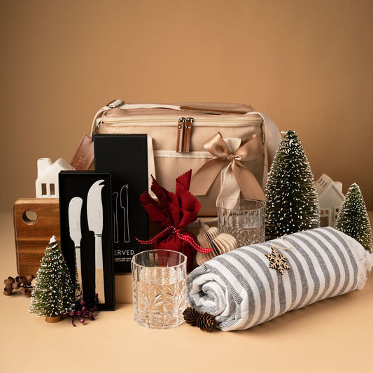 cooler bag gift with glasses, towel, knives and pudding on display in front of gold background
