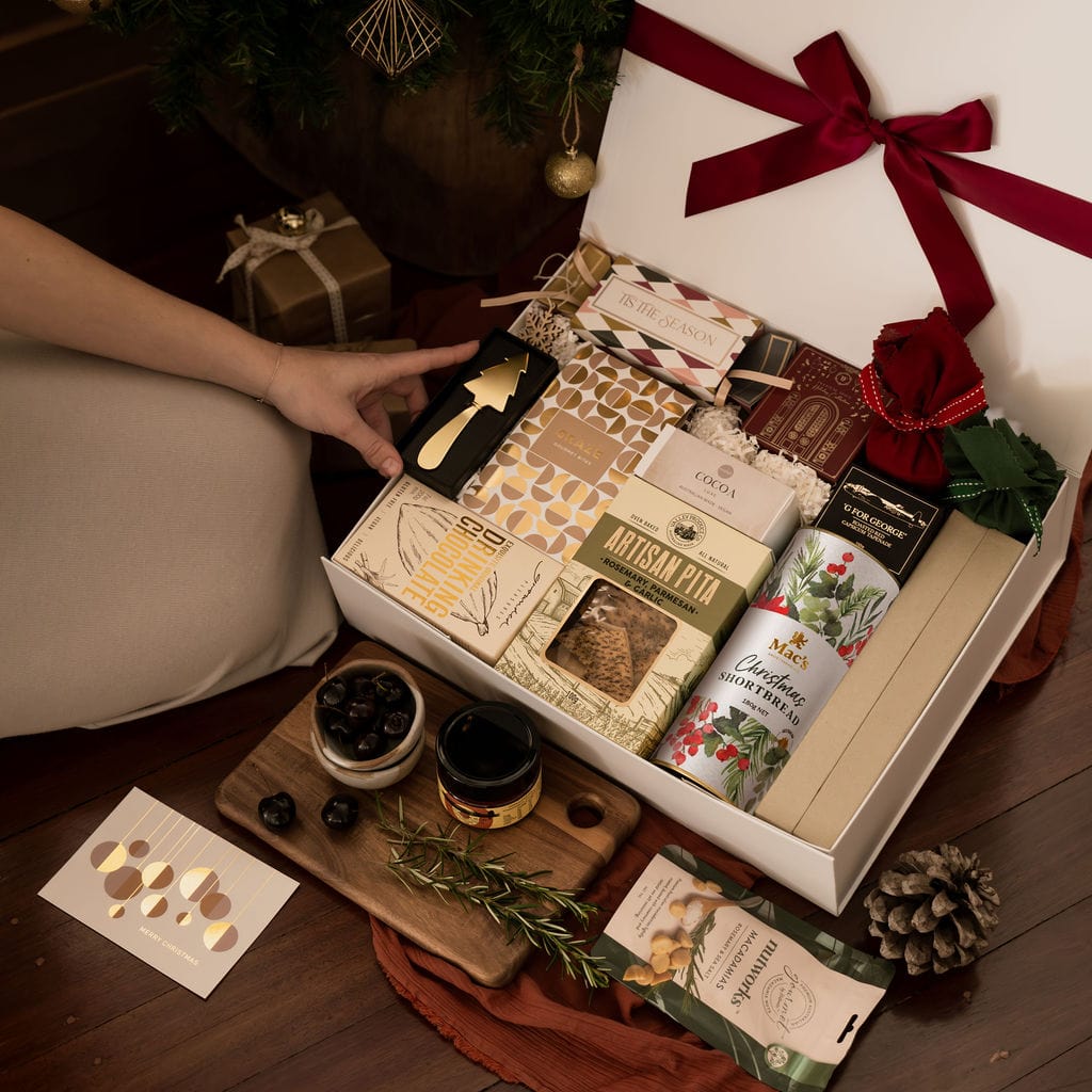 woman kneeling next to an open christmas gift box showing contents 