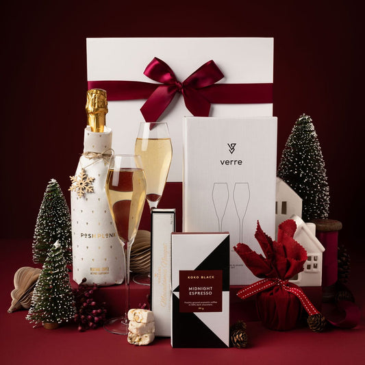 red and white themed christmas gift with sparkling wine, champagne glasses and chocolate on display in front of the box