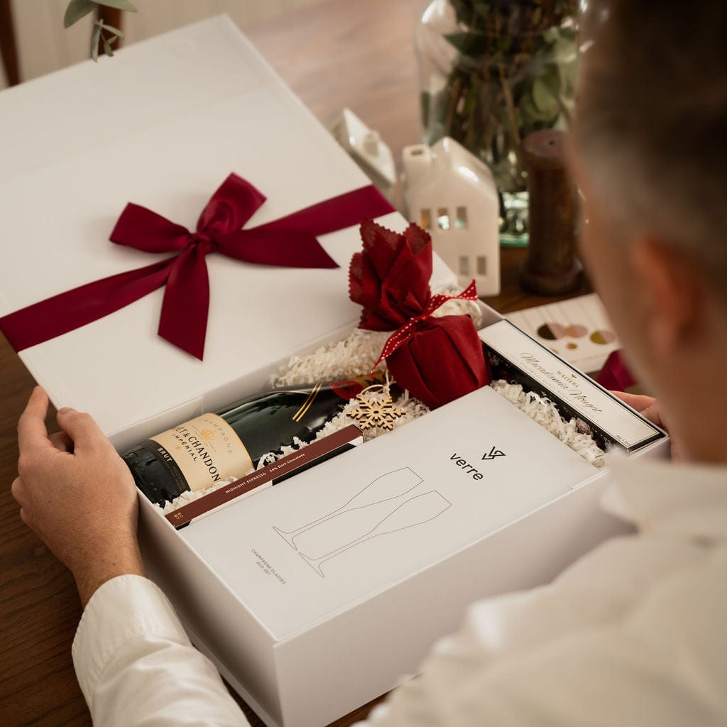 man opening christmas gift box to show contents and red ribbon 