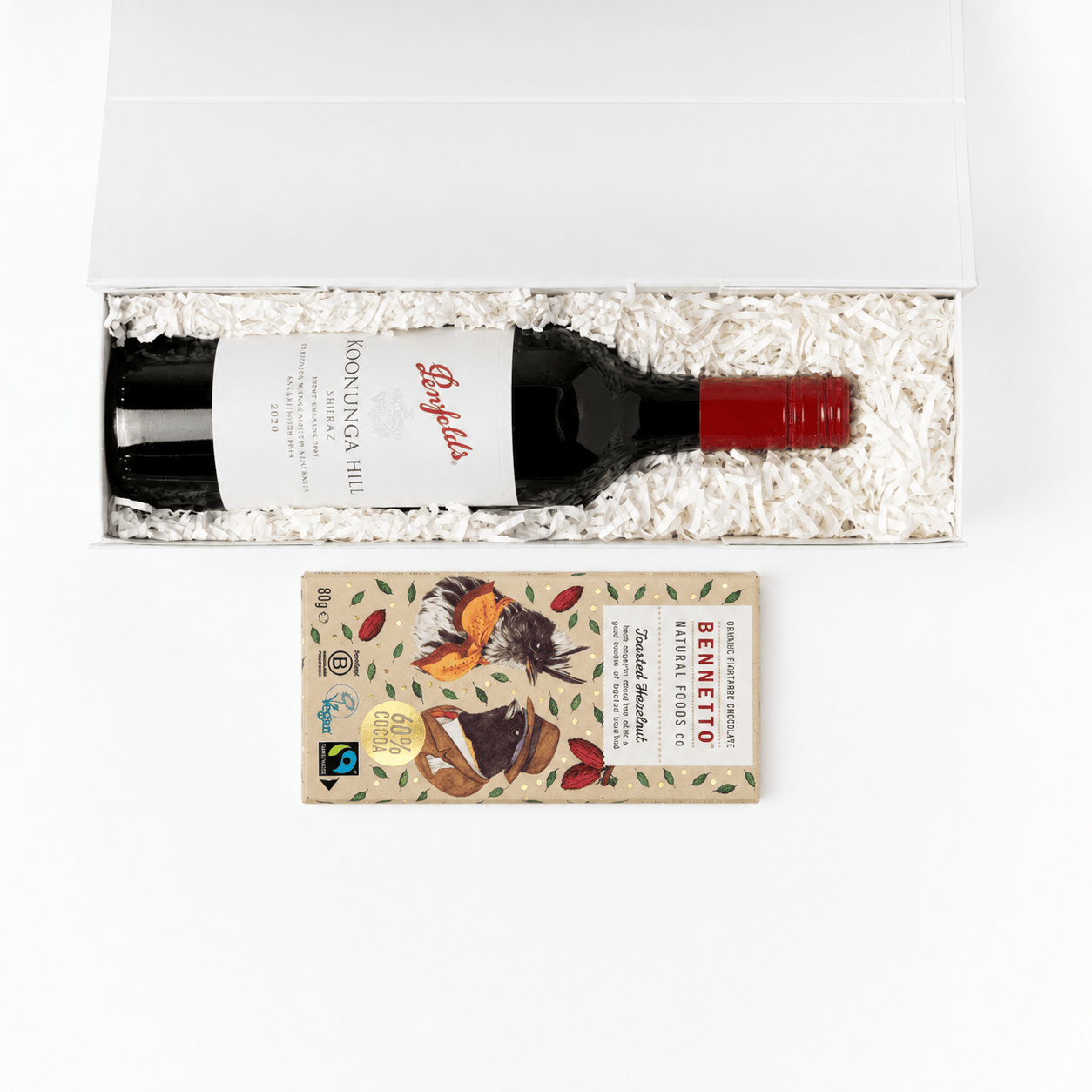 A gift set containing a bottle of Penfolds Booming Hill red wine and a Ritter Sport chocolate bar, presented in a white box with white crinkle paper packing inside a clean white studio background.