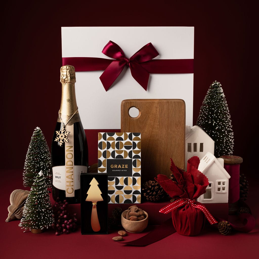 red themed christmas gift with chandon, wooden board, pudding and gold tree knife on display