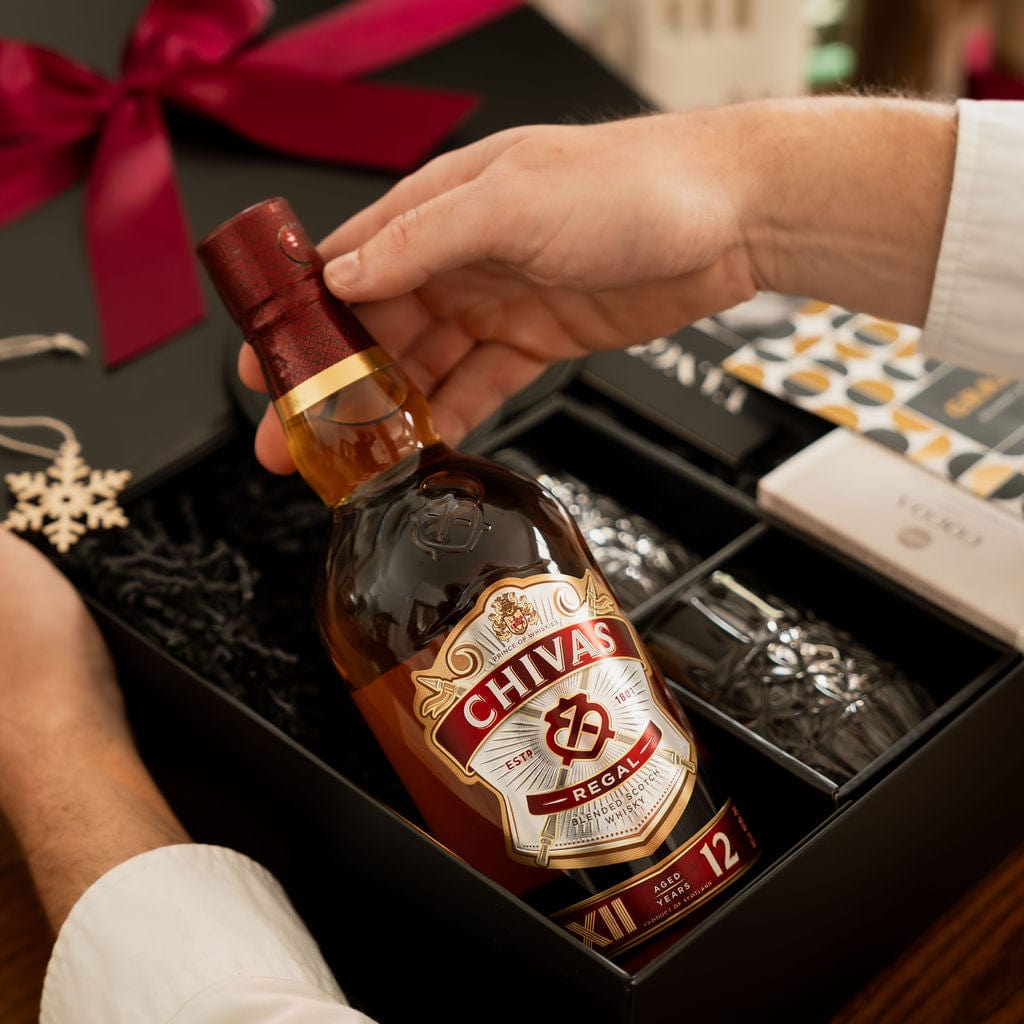 hand holding chivas whisky as part of christmas gift box