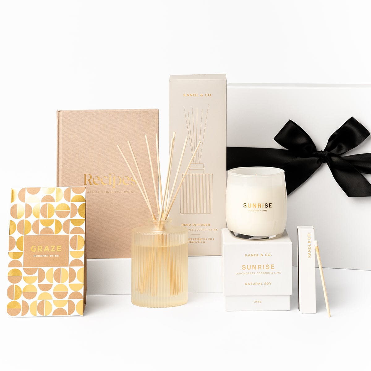 The reset gift box in light pink tones, with a reed diffuser, soy candle, recipe journal, long matches and graze gourmet bites. 