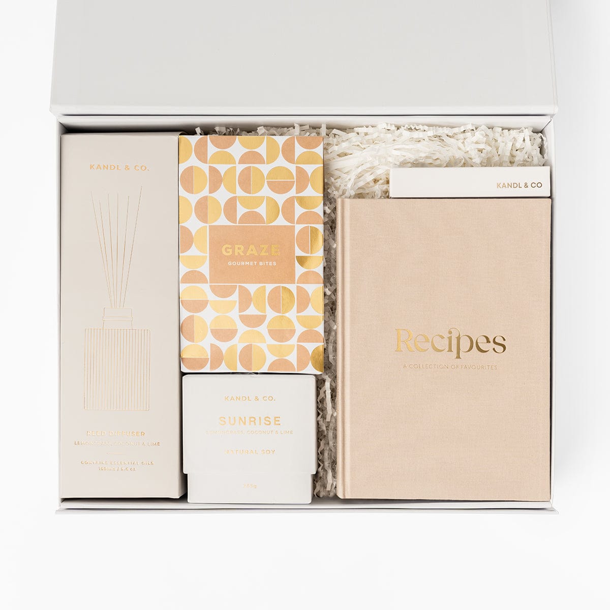 The reset gift box in light pink tones, with a reed diffuser, soy candle, recipe journal, long matches and graze gourmet bites. 